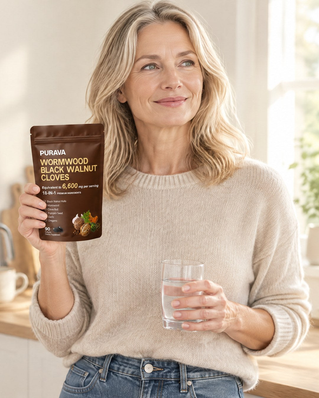 A woman in her kitchen in the morning, holding a PURAVA pouch and a glass of water